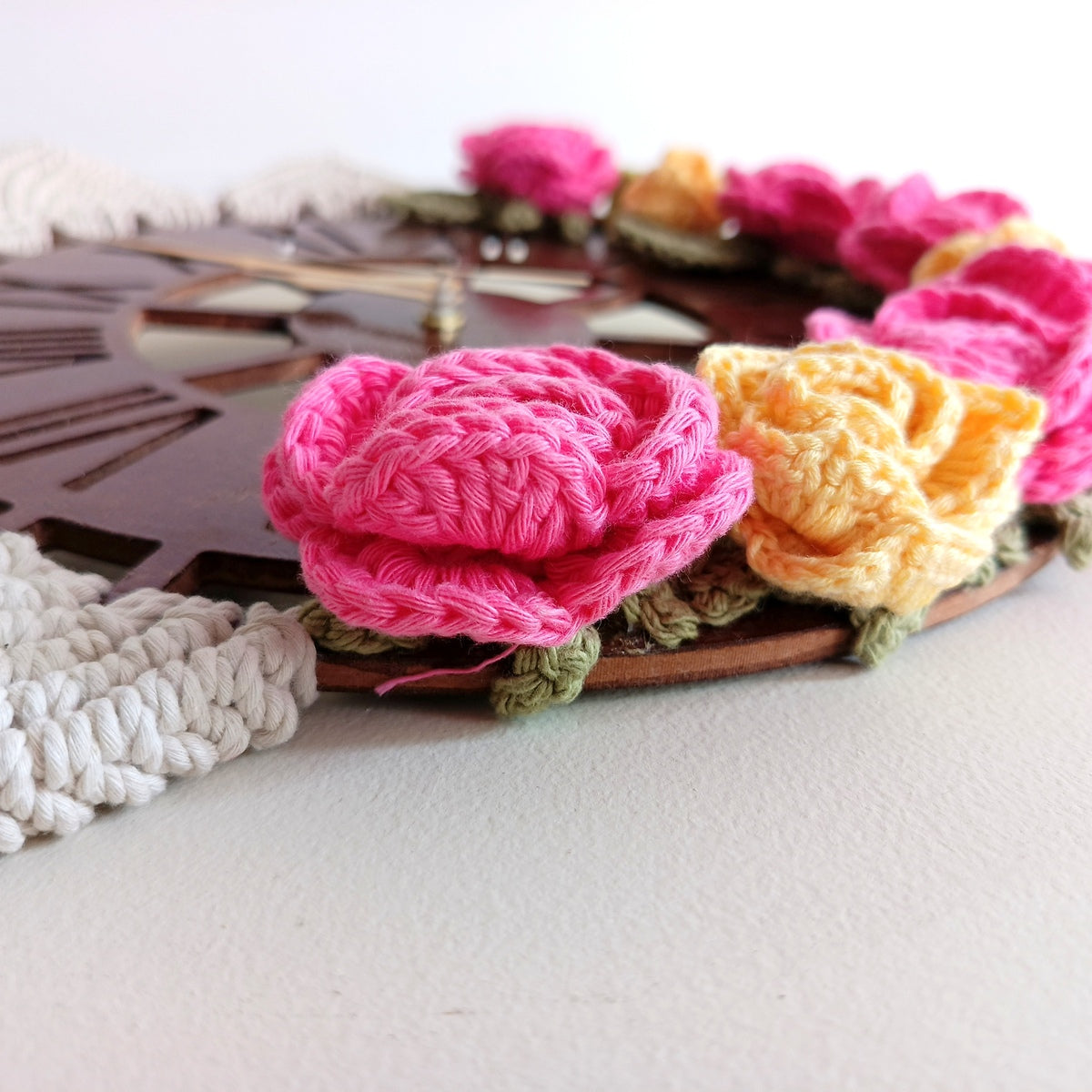Colorful crocheted flowers on a wooden board with a neutral background