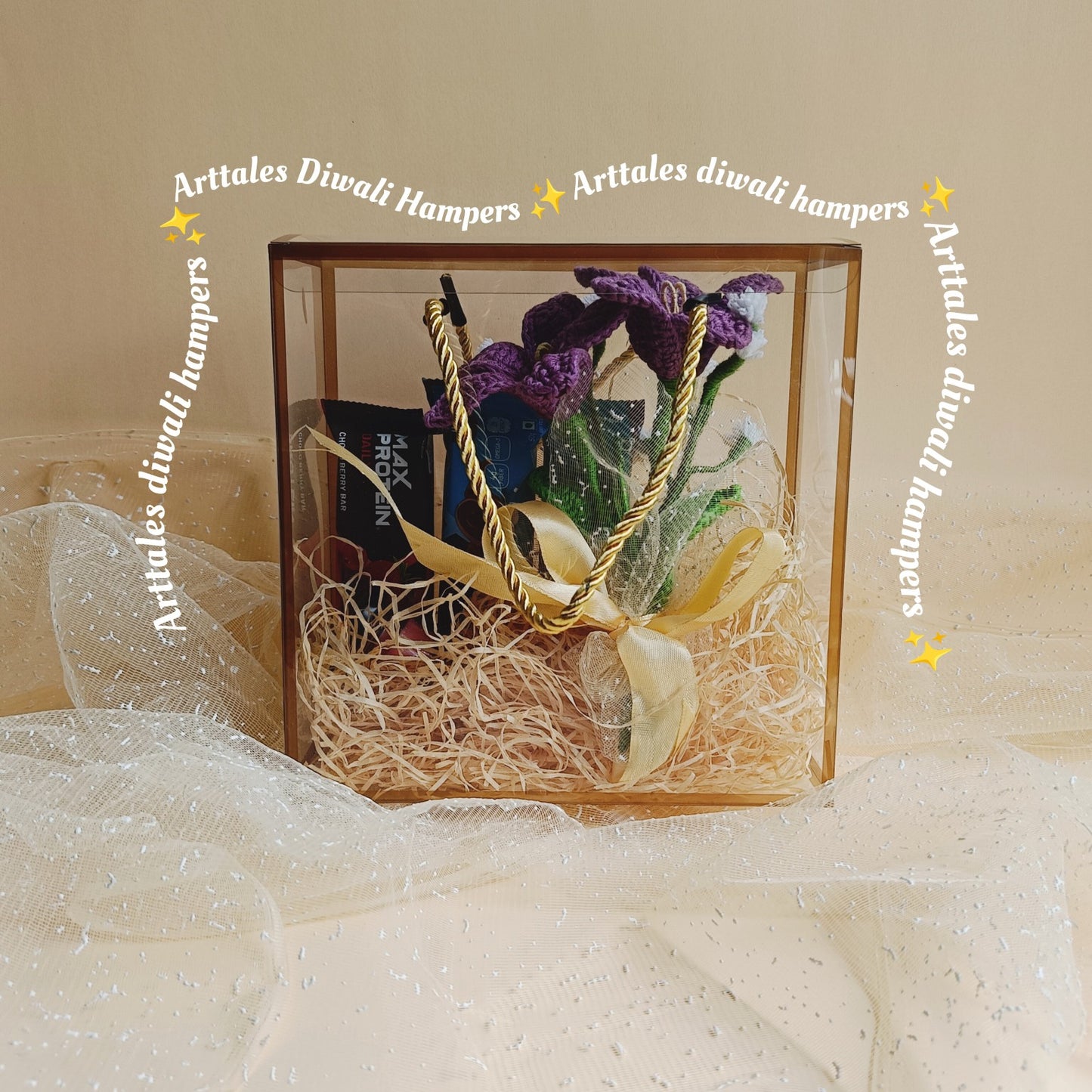 Decorative box with flowers and ribbons on a beige background, featuring 'Arttales Diwali Hampers' text.