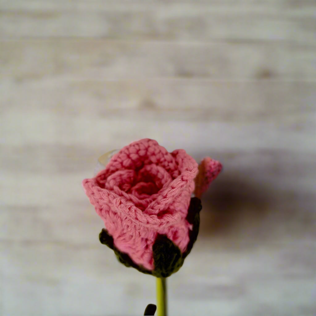 Knitted pink rose on a textured white background