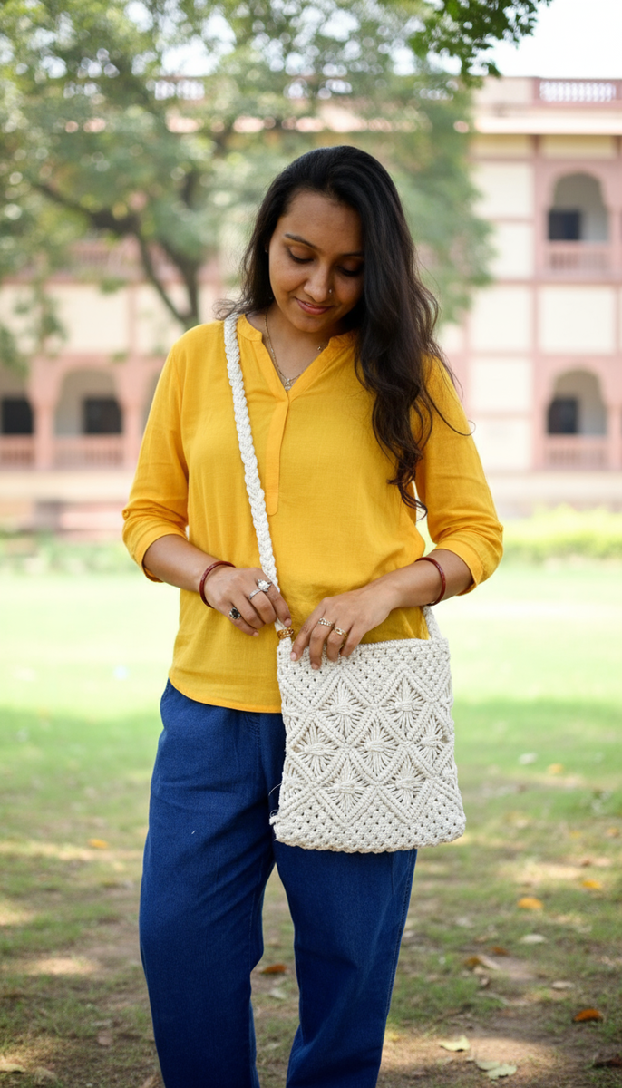 Woman holding a white macrame bag outdoors with a building in the background