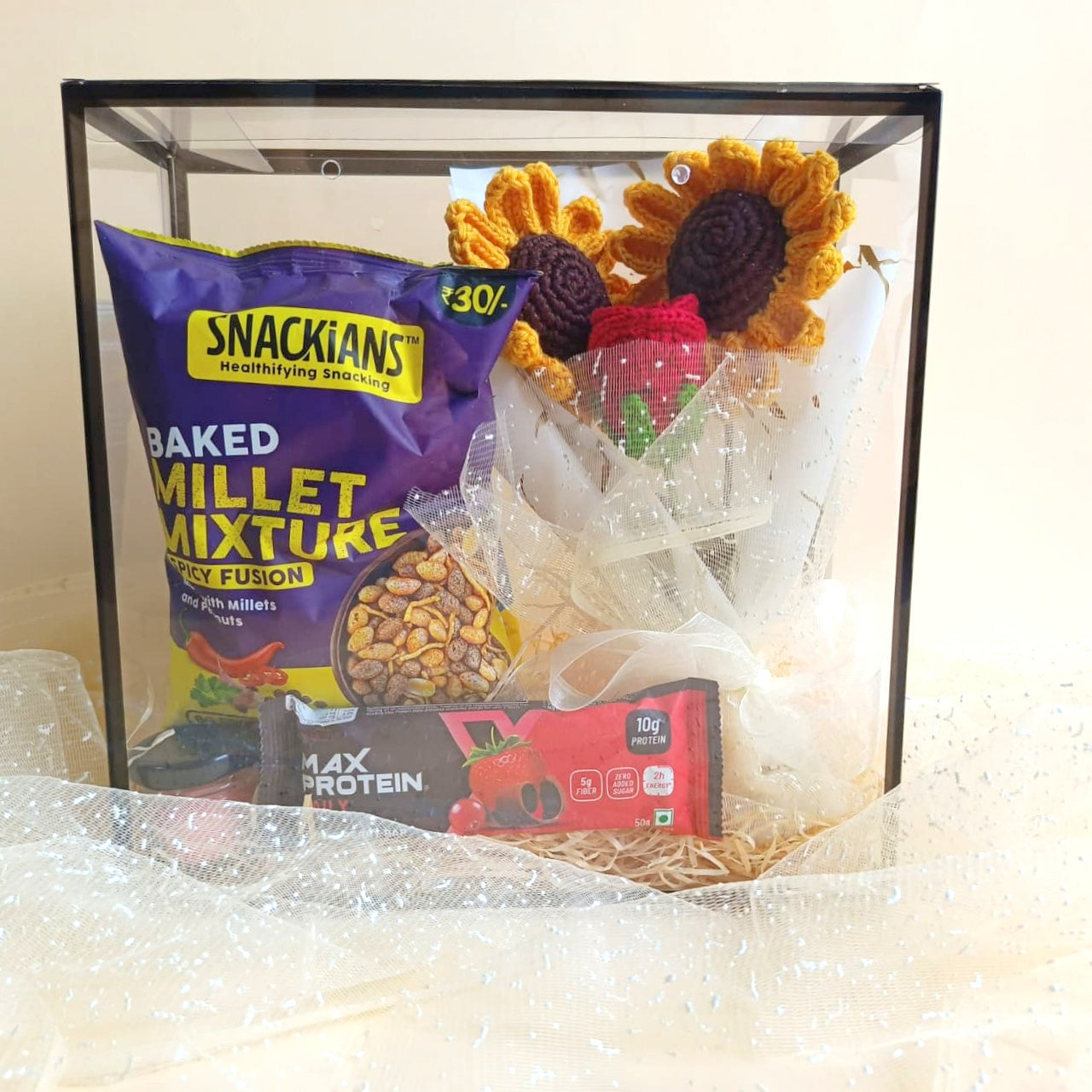gul crochet flowers, Snack box with Snackians millet mixture and Max Protein package under a glass cover