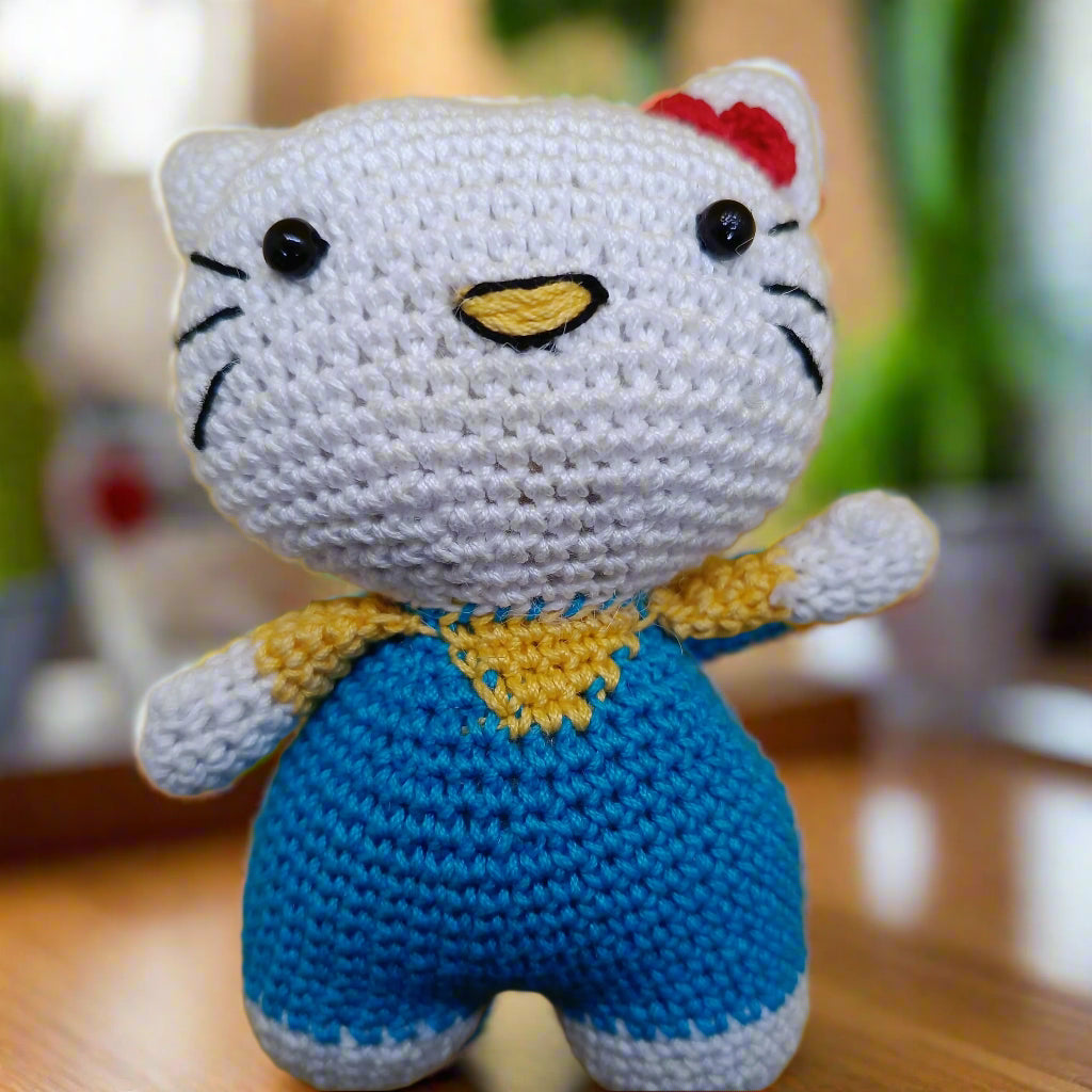 Crocheted Hello Kitty toy with a blue outfit and red bow