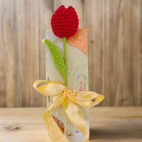Crocheted red tulip flower on a wrapped gift with a yellow ribbon 