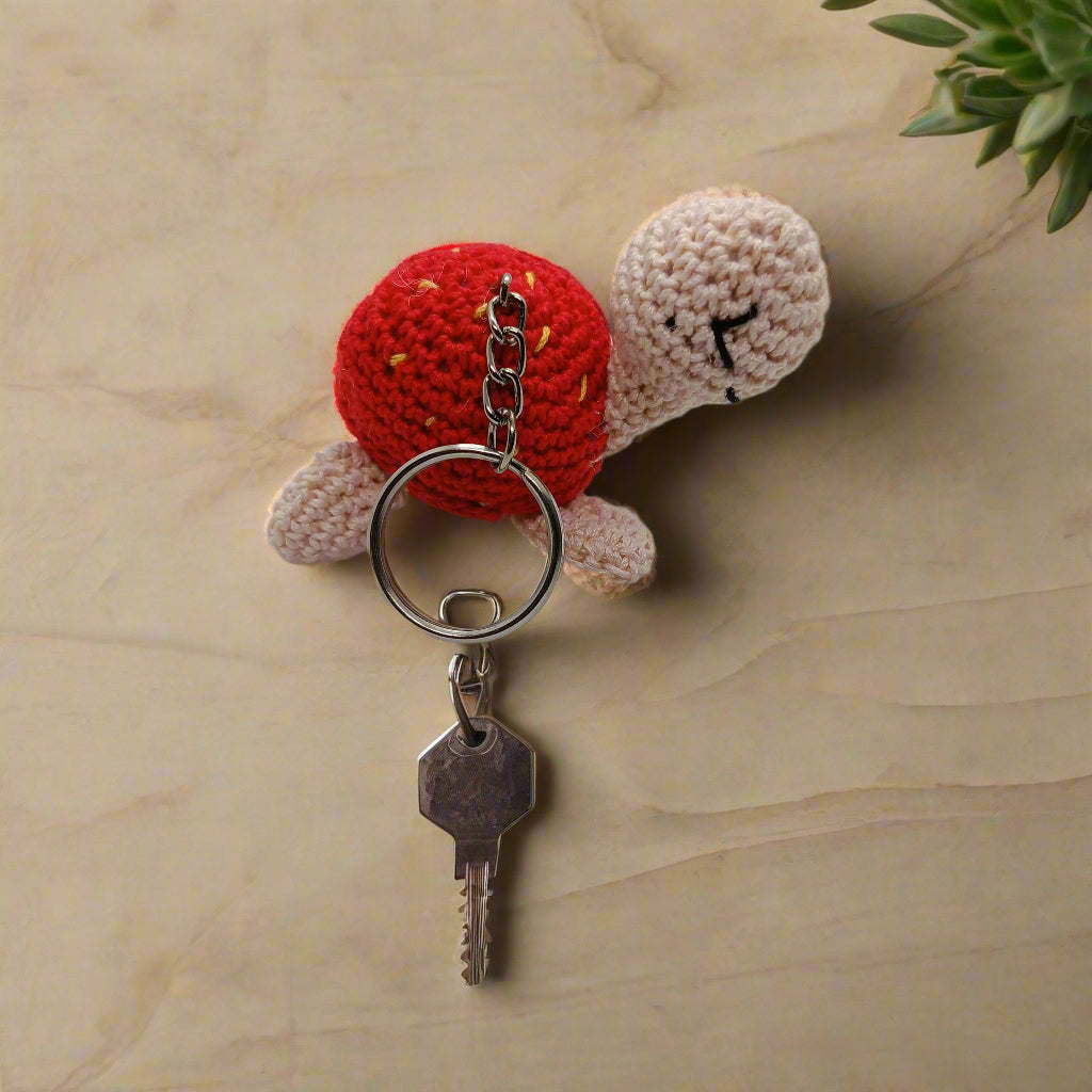 Crocheted turtle keychain with red shell and beige body 
