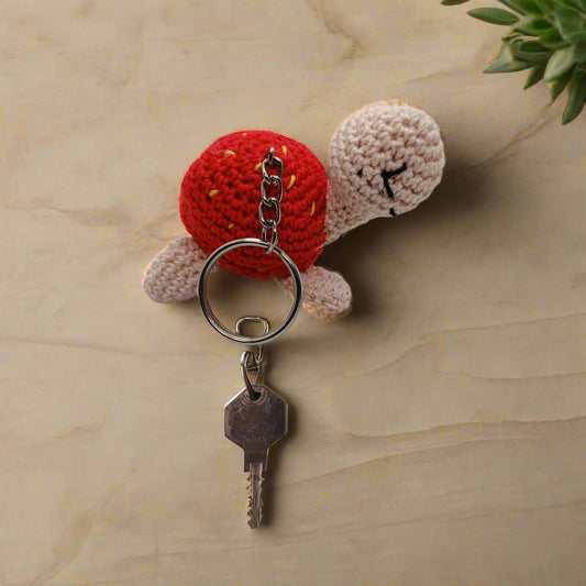 Crocheted turtle keychain with red shell and beige body 